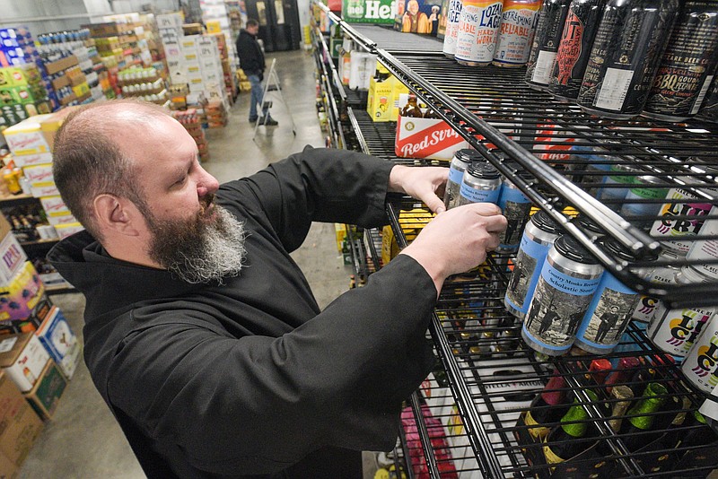 Brother Sebastian Richey with Country Monks Brewing surveys the beer for sale on Wednesday at Sodie’s Wine and Spirits in Fort Smith. Based in Subiaco, the brewery has begun distributing its craft beers, including Isidor Red Ale, Abbey Amber, Scholastic Stout and Peter’s Chair Pale Ale, to Sodie’s and to Circle S Foods in Paris.
(NWA Democrat-Gazette/Hank Layton)