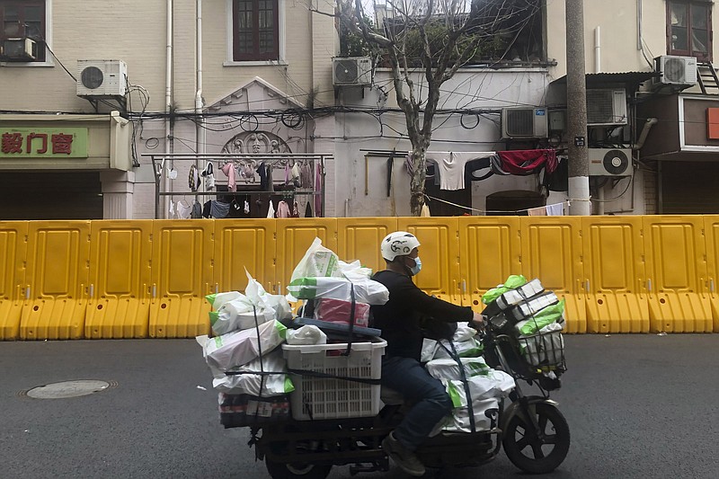 A delivery man passes barriers set up to lock down a community in Shanghai last month.
(AP)