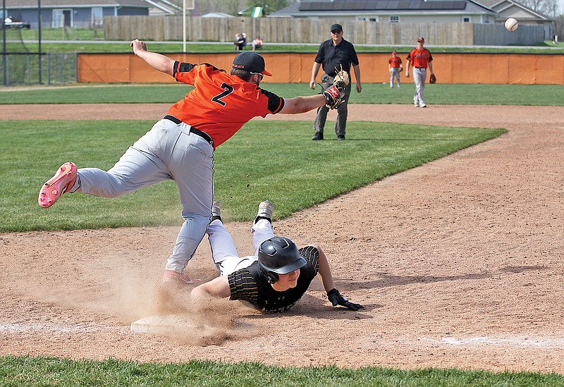 St. Elizabeth’s Brock Lucas dives safely back into first base as the ball on a pickoff attempt gets away from New Bloomfield first baseman Michael Leason during Saturday’s game at Haley Field in New Bloomfield. (Greg Jackson/News Tribune)