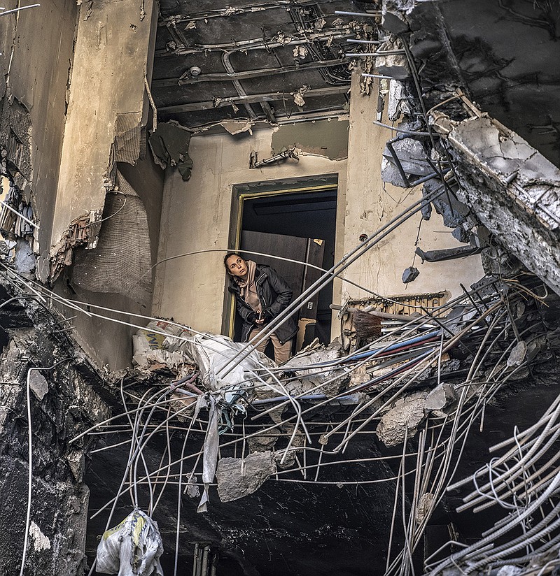 A woman looks out from an apartment building Friday after an overnight Russian missile strike in central Kyiv, Ukraine. More photos at arkansasonline.com/ukrainemonth3/.
(The New York Times/David Guttenfelder)