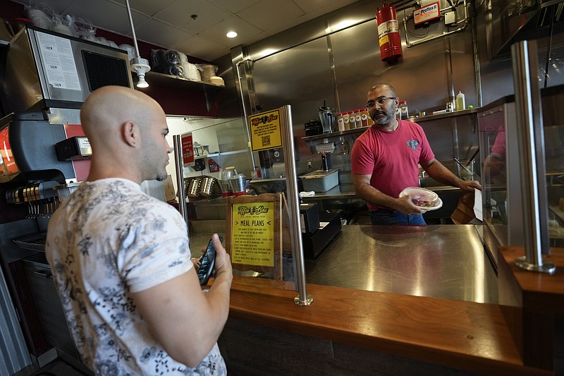 Anesh Bodasing, owner of the fast-casual Indian restaurant Tiffin Box, serves a customer last month in West Palm Beach, Fla. Bodasing is thinking about installing an automated kiosk for ordering and payments after his staff dwindled to three workers.
(AP/Rebecca Blackwell)