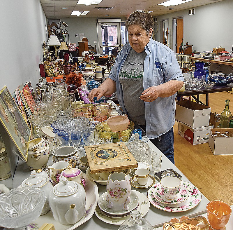 Donna Deetz, president of the Historic City of Jefferson, shows some of the glassware and other items for sale as HCJ prepares to hold a rummage sale in the organization's annex at 601 E. High St. on Saturday, May 14, 2022. Volunteers have been sifting through the items --  sorting, organizing and pricing them this week. Some pieces are considered very collectible, some items are antique while many are everyday items donated to the fundraising cause. (Julie Smith/News Tribune photo)