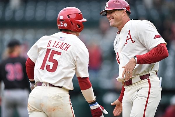 Arkansas catcher Dylan Leach is congratulated by assistant coach Nate Thompson Wednesday, April 20, 2022, after hitting a two-run home run scoring left fielder Jace Bohrofen during the second inning against Arkansas State at Baum-Walker Stadium in Fayetteville.