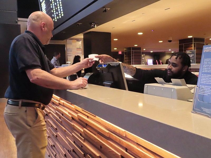 A customer receives a betting ticket in the sports betting lounge at the Tropicana casino in Atlantic City N.J. on Thursday, May 12, 2022. American gamblers have wagered over $125 billion on sports with legal betting outlets in the four years since the U.S. Supreme Court cleared the way for all 50 states to offer legal sports betting; about two thirds currently do. (AP Photo/Wayne Parry)