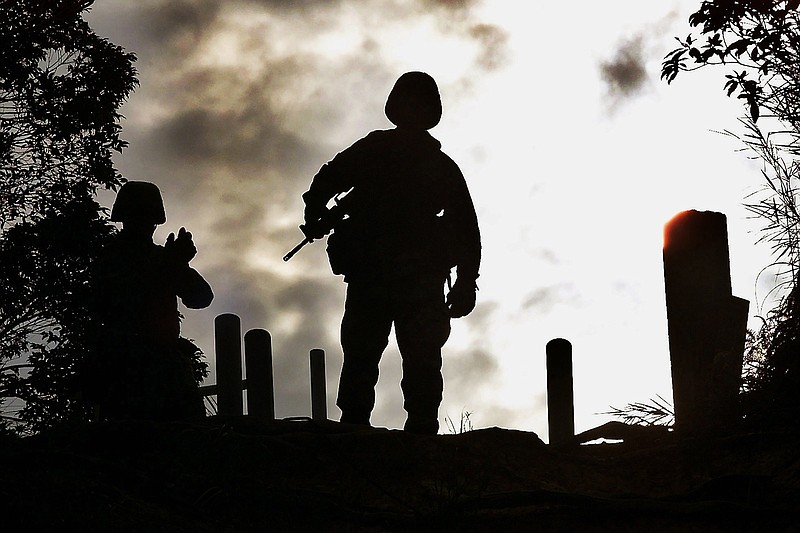 U.S. Marine Corps Sgt. Mike Anglen of Turner, Ore., (right) stands atop a cliff as Sgt. Bryan Wallace of Pikin, Ill., waits for his turn before their rappelling exercise at Jungle Warfare Training Center in Camp Gonsalves, northern Okinawa, Japan, on Feb. 8, 2002.
(AP File Photo/Junji Kurokawa)