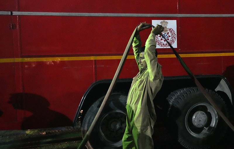 A fire official carries water pipe to douse a fire in a four storied building, in New Delhi, India, Saturday.
(AP/Manish Swarup)