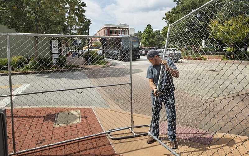Jacob Teter with Tulsa-based Aim Right Temporary Site Services sets up fencing in preparation for demolition of the Tucker's Corner building on the Bentonville square in this Sept. 19, 2019 file photo. Developers are planning to use the site for a new hotel, tentatively scheduled to open in summer 2024. (NWA Democrat-Gazette/Ben Goff)