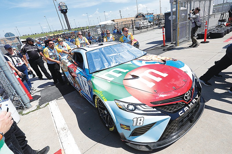 Kyle Busch's No. 18 car is pushed to the track by crew members before a practice run Saturday for a NASCAR Cup Series race at Kansas Speedway in Kansas City, Kan. (Associated Press)