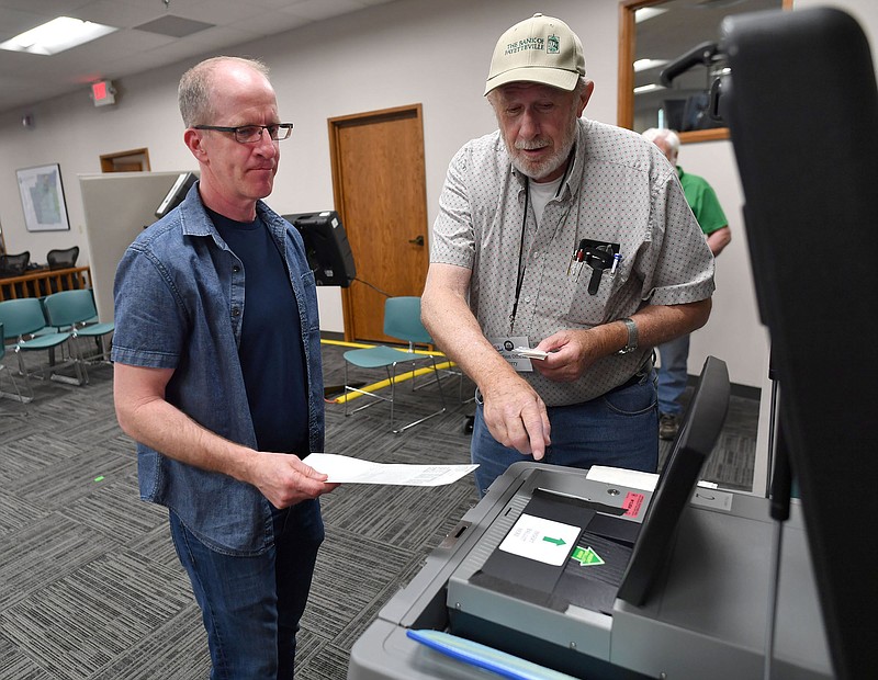 Joe Michie (left) of Fayetteville places his ballot in the ballot box Friday, May 13, 2022, with assistance from a poll worker who did not wish to be identified after early voting at the Washington County Courthouse in Fayetteville.  (NWA Democrat-Gazette/Andy Shupe)