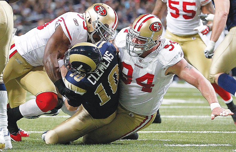 In this Jan. 1, 2012, file photo, 49ers defensive end Justin Smith (94) gets help from teammate NaVorro Bowman to sack Rams quarterback Kellen Clemens during a game in St. Louis. (Associated Press)