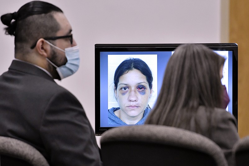 An image of Britany Barron is shown on a computer screen as her husband Armando Barron looks toward the jury during opening arguments in his trial at Cheshire County Superior Court, Tuesday May 17, 2022, in Keene, N.H. Barron, who plead not guilty, is on trial on charges of killing his wife's male co-worker after he discovered they were texting, and then forcing her to behead him after she drove with the body for 200 miles to a remote campsite. (AP Photo/Josh Reynolds, Pool)