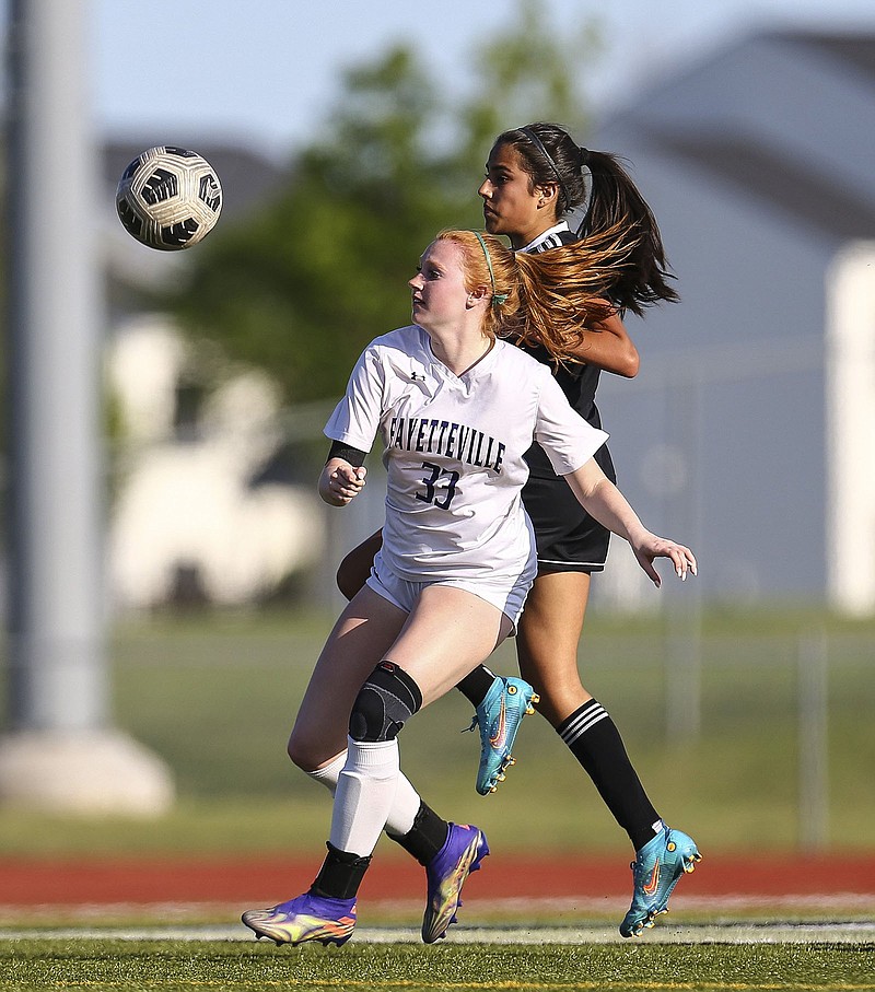 Fayetteville’s Elizabeth Weir (front) jostles with a Bentonville player for control of the ball during the Lady Bulldogs’ match against the Lady Tigers on April 26 in Bentonville. Fayetteville will play Bentonville West for a third time this season in Saturday’s Class 6A state championship game in Benton. (Special to the NWA Democrat-Gazette/David Beach)