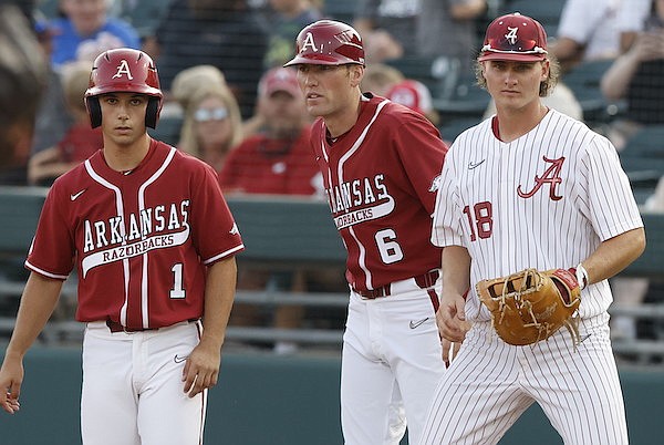 Arkansas' Robert Moore (left) speaks with volunteer coach Bobby Wernes (center) as Alabama first baseman Drew Williamson covers during a game Friday, May 20, 2022, in Tuscaloosa, Ala. (Photo courtesy Alabama Athletics, via SEC Media Portal)