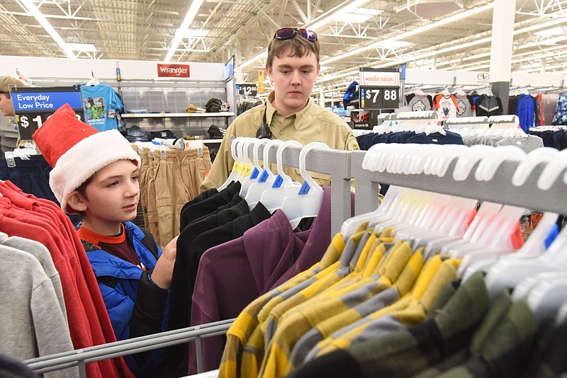 Devin Rust-Hagar, 10, picks out a sweatshirt while shopping with Deputy Jacob Dixon of the Benton County sheriff's office in this Dec. 7, 2021 file photo. (NWA Democrat-Gazette/Flip Putthoff)