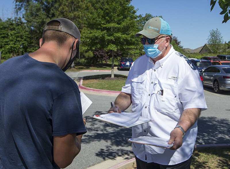 Jonathan Anderson (right) of Tucson, Ariz., with National Ballot Access takes a signature from David Wallace of Rogers while canvassing outside the Bentonville Revenue Office in this May 29, 2020 file photo. (NWA Democrat-Gazette/Ben Goff)