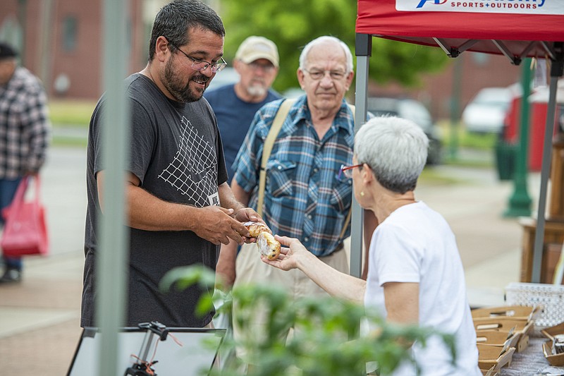 Matt Mewton of Van Buren purchases baked goods from merchant Kathy Mazyck on Saturday, May 21, 2022, at the Fort Smith Farmers Market in downtown Fort Smith. The event features vendors selling produce, flowers, crafts and other homemade or homegrown products and is open every Saturday morning year-round, as well as on Wednesday mornings during the summer. Visit nwaonline.com/220522Daily/ for today's photo gallery..(NWA Democrat-Gazette/Hank Layton)