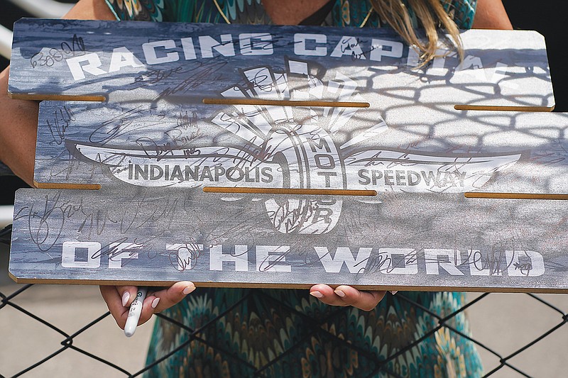Kirstin Kendall holds a sign as she seeks autographs during Monday's practice for the Indianapolis 500 at Indianapolis Motor Speedway in Indianapolis. (Associated Press)