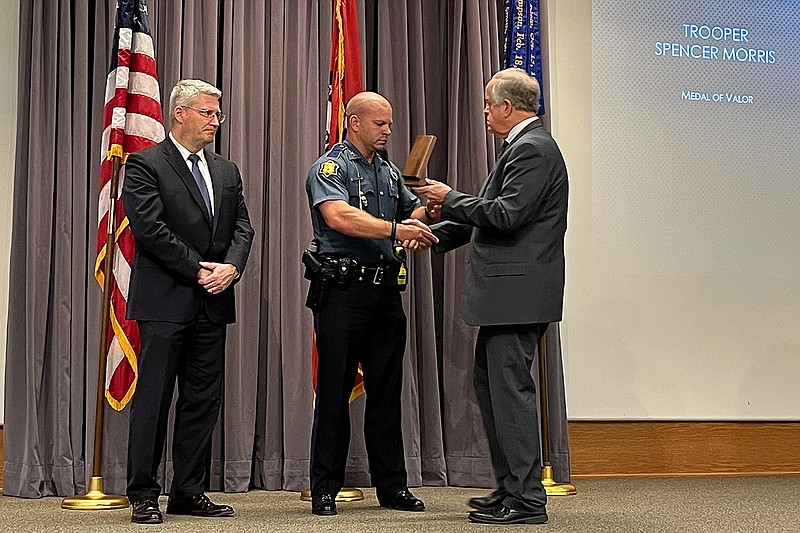 Arkansas State Police Trooper Spencer Morris receives the agency’s Medal of Valor from state police director Col. Bill Bryant (right) on Wednesday, as James Dawson, FBI special agent in charge of the Little Rock field office, looks on. Morris was also named Trooper of the Year by the state police agency for his actions during a pursuit in December in which he was shot by a suspect.
(Arkansas Democrat-Gazette/Grant Lancaster)
