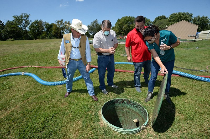 Kim Patulak (right), human resources director for the city of Springdale, holds open a manhole at the former Bethel Heights wastewater treatment facility in this Aug. 21, 2020 file photo. Joining Patulak are (from left) Heath Ward, executive director of Springdale Water Utilities; Chris Clark, financial analyst for Springdale Water Utilities; and Al Drinkwater, a volunteer environmental consultant. (NWA Democrat-Gazette/Andy Shupe)
