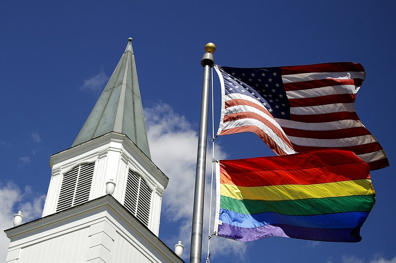 A gay pride rainbow flag flies along with the U.S. flag in front of the Asbury United Methodist Church in Prairie Village, Kan., in this April 19, 2019 file photo. (AP/Charlie Riedel)