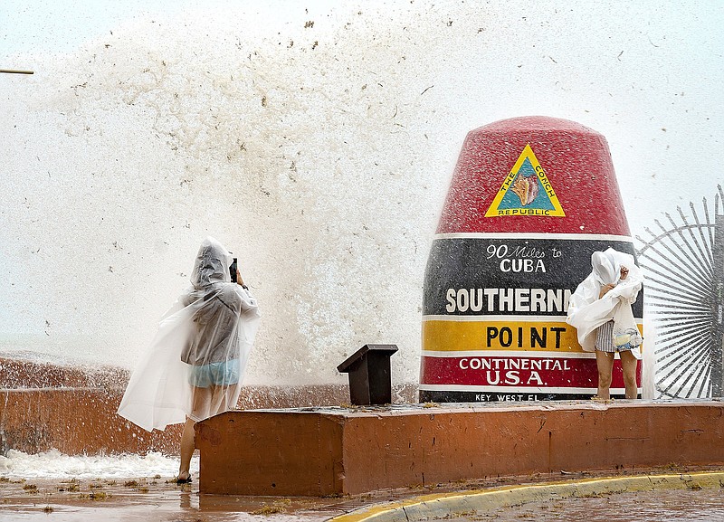 Vistors to the Southernmost Point buoy in Key West, Fla., brave the waves Friday for photos as the island chain was under a tropical storm warning on Friday.
(AP/The Key West Citizen/Rob O’Neal)