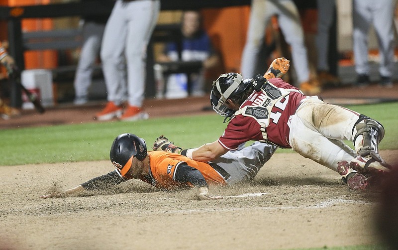 Arkansas Michael Turner (12) attempts to tag out Oklahoma State Hueston Morrill (1), Sunday, June 5, 2022 during the ninth inning of the NCAA Baseball Stillwater Regional at O'Brate Stadium in Stillwater, Okla. Check out nwaonline.com/220606Daily/ and nwadg.com/photos for a photo gallery...(NWA Democrat-Gazette/Charlie Kaijo)