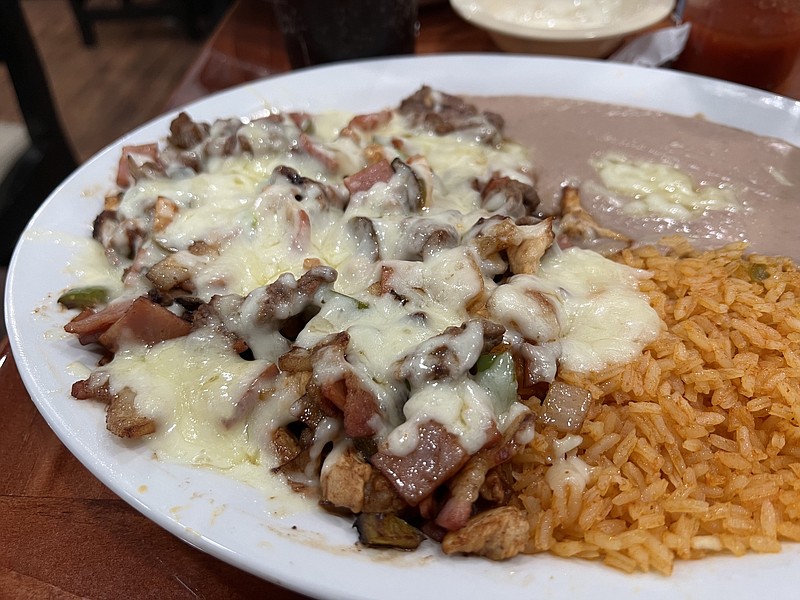 The "mixed" Alambre at Mar y Tierra Cantina & Grill comes with chicken, steak, bacon, ham, green peppers and onions, topped with a thick layer of melted cheese, plus rice and refried beans. (Arkansas Democrat-Gazette/Eric E. Harrison)