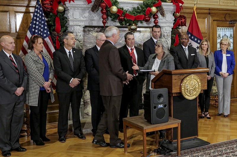 Gov. Asa Hutchinson (fifth from left) receives the final Arkansas School Safety Commission report from commission chair Dr. Cheryl May (fourth from left) at the state Capitol in Little Rock in this Dec. 3, 2018 file photo. Hutchinson has reinstated the commission in response to the May 24, 2022 school shooting in Uvalde, Texas. (Arkansas Democrat-Gazette file photo)