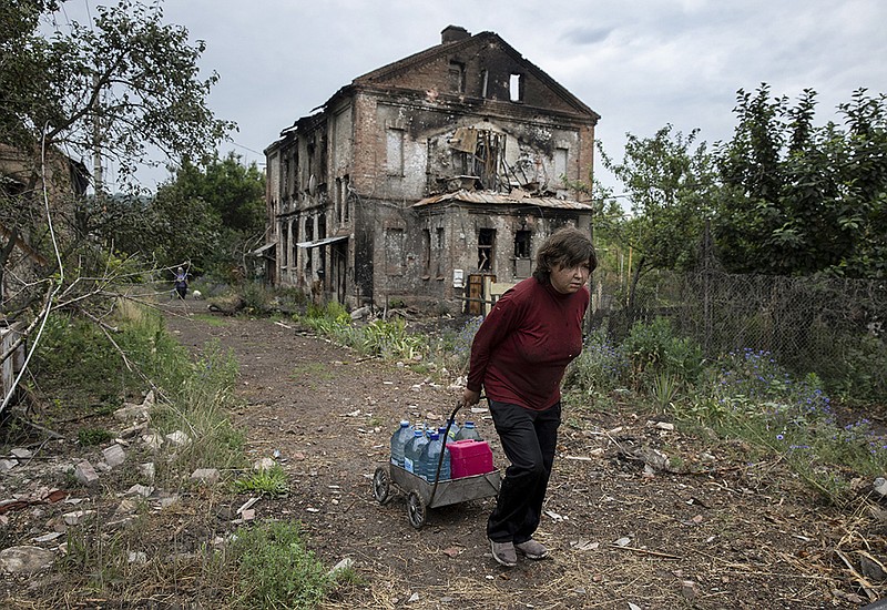 A woman carries water past destroyed buildings Wednesday in Lysychansk in the Donetsk region of eastern Ukraine, where Russian and Ukrainian forces continue to trade bombardments. A majority of the population has fled the area. More photos at arkansasonline.com/ukrainemonth4/.
(The New York Times/Tyler Hicks)