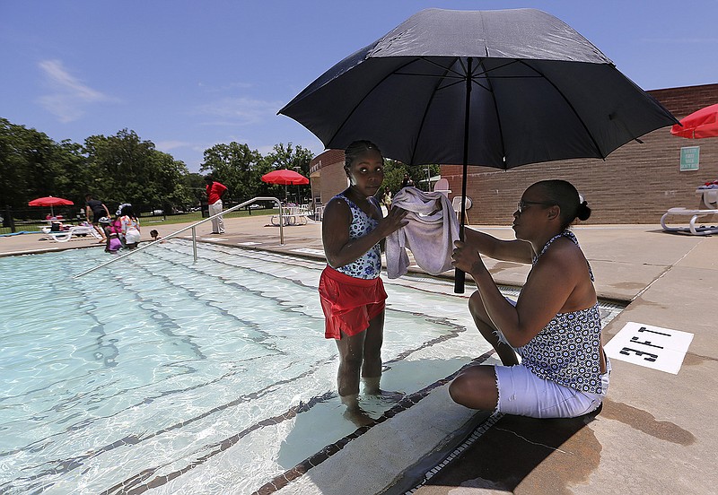 DeAngela Reed sits under an umbrella to shade herself from the sun as she hands her daughter, McKaylyn, 9, a towel to wipe her face coming out of the pool on Wednesday at the Southwest Community Center in Little Rock.
(Arkansas Democrat-Gazette/Thomas Metthe)