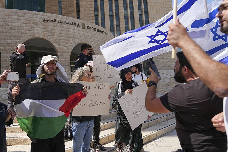 Supporters of Mohammed el-Halabi hold a Palestinian flag and placards as protesters wave Israeli flags on Wednesday, outside the district court in the southern Israeli city of Beersheba.
(AP/Tsafrir Abayov)