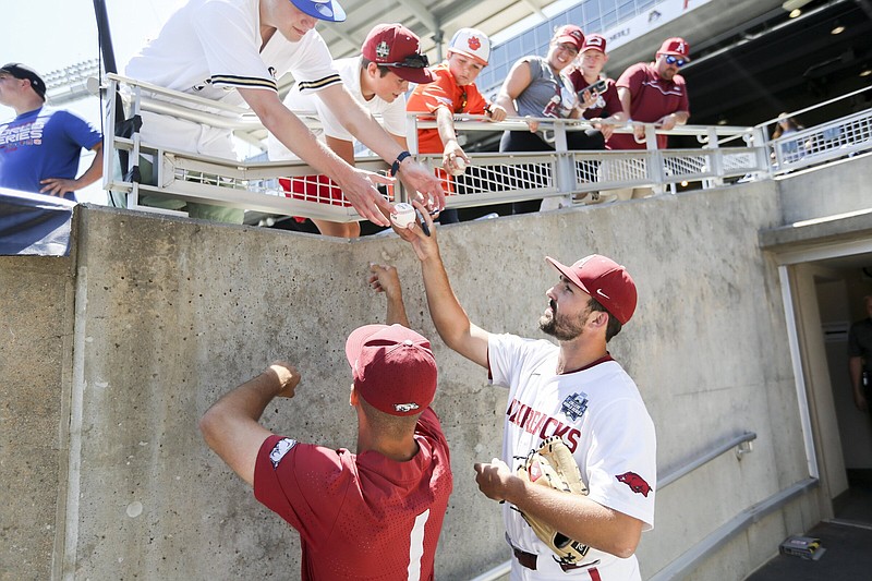 Arkansas pitcher Connor Noland (right) and second baseman Robert Moore sign autographs after a practice session Thursday at Charles Schwab Field in Omaha, Neb., site of the College World Series. Noland will start on the mound for the Hogs in their CWS opener against Stanford on Saturday. More photos available at arkansasonline.com/617cwspractice.
(NWA Democrat-Gazette/Charlie Kaijo)