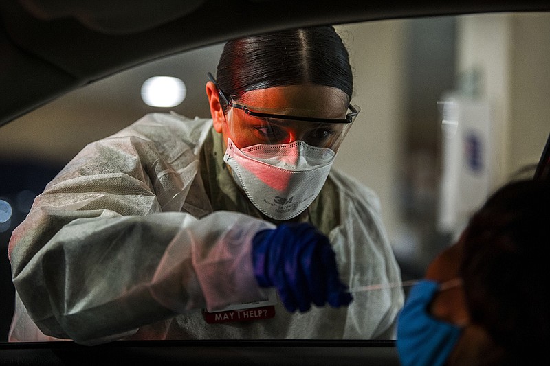Audriana Morina, with the Arkansas Army National Guard, administers a test for COVID-19 at a drive-thru screening site at UAMS in this file photo from Tuesday, Jan. 4, 2022.(Arkansas Democrat-Gazette/Stephen Swofford)