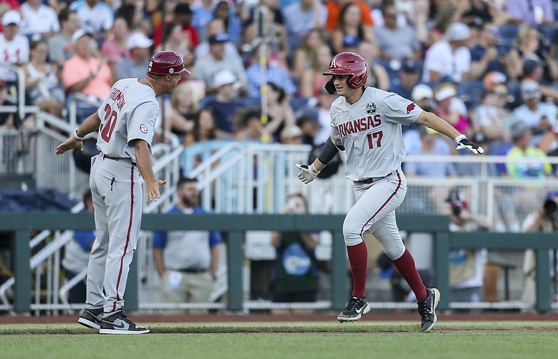 Arkansas’ Brady Slavens is congratulated by third-base coach Nate Thompson after hitting a home run in the fifth inning against Ole Miss at the College World Series on Wednesday night in Omaha, Neb. The home run to center field was measured at 436 feet. More photos available at arkansasonline.com/623cws.
(NWA Democrat-Gazette/Charlie Kaijo)
