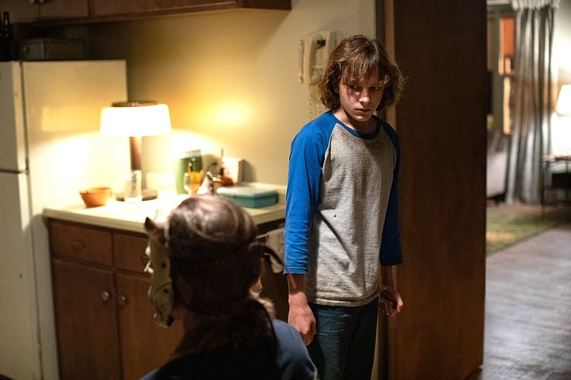 A serial child kidnapper called “The Grabber” (Ethan Hawke, back to camera) and his latest victim, 13-year-old Finney (Mason Thames), share a moment in Scott Derrickson’s “The Black Phone.”