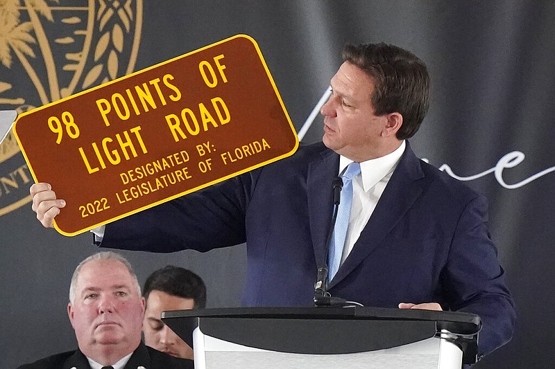Florida Gov. Ron DeSantis holds up a sign dedicated to the 98 people who lost their lives during a remembrance event at the site of the Champlain Towers South building collapse in Surfside, Fla., on Friday, June 24, 2022, the anniversary of the oceanfront condo building collapse that killed 98 people in Surfside. (AP/Wilfredo Lee)
