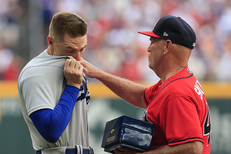 Freddie Freeman of the Dodgers reacts as he is presented his World Series championship ring by Braves manager Brian Snitker before the start of Friday night's game in Atlanta. (The Associated Press)