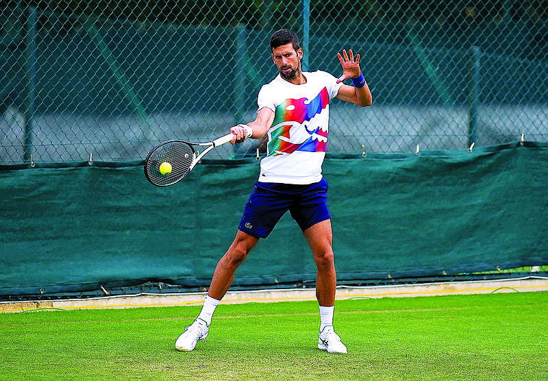 Novak Djokovic hits a return during practice Saturday at the All England Lawn Tennis and Croquet Club in London. (The Associated Press)