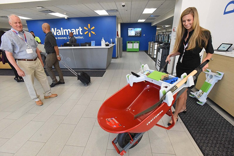 Mollie Thorsen and her father, Bob Thorsen, show off a Burro Buddy on Wednesday — it fits on a wheelbarrow to carry gardening or construction tools — after pitching the product to Walmart associates at Wednesday’s Open Call event in Bentonville.
(NWA Democrat-Gazette/Flip Putthoff)