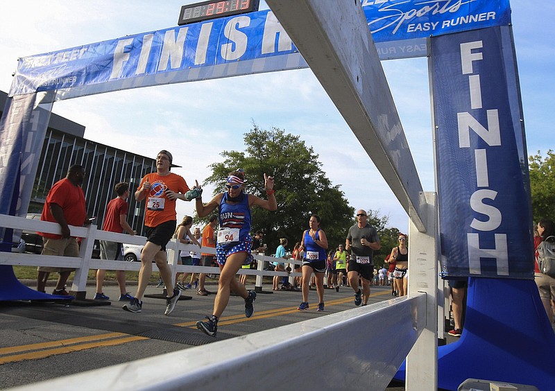 Runners cross the finish line during the 2019 Firecracker Fast 5K in Little Rock. This year’s race, a Fourth of July staple for over 40 years, resumes a downhill start and is set to begin at 7:30 a.m. Monday.
(Arkansas Democrat-Gazette/Staton Breidenthal)