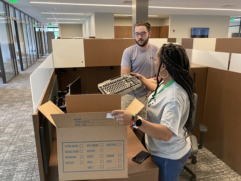 Carla McCoy Roaf hands a keyboard to Christian Young on Friday as the two IT workers get another workstation ready at the new Relyance Bank location in White Hall. (Pine Bluff Commercial/Byron Tate)