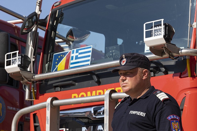 A Romanian firefighter stands in front of fire engines during a ceremony on Saturday in Athens.
(AP/Yorgos Karahalis)