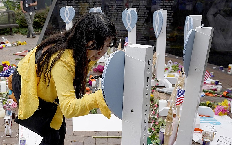 Yesenia Hernandez, granddaughter of Nicolas Toledo, who died in the parade shooting Monday in Highland Park., Ill., writes on a memorial Wednesday for Toledo and the six others who were killed. More photos at arkansasonline.com/77highland/.
(AP/Charles Rex Arbogast)