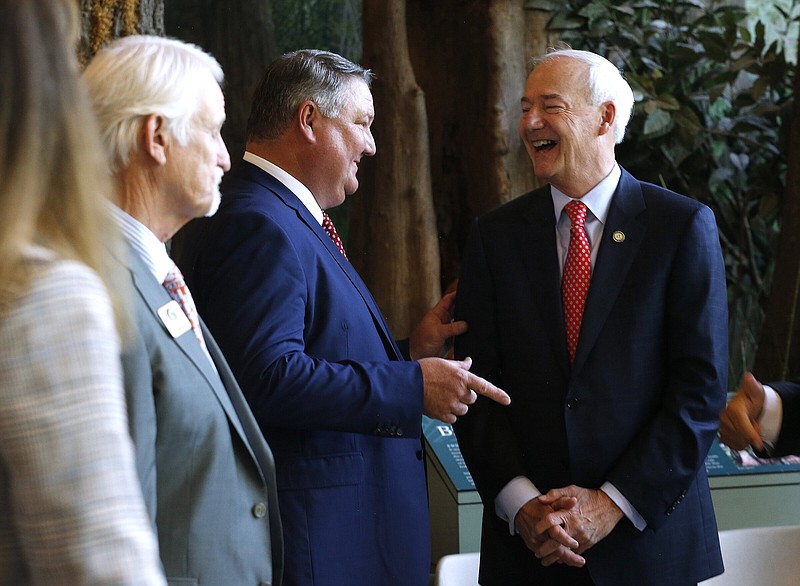 Bill Jones (center) of Pine Bluff laughs with Gov. Asa Hutchinson (right) after Hutchinson announced the appointment of Jones to the Arkansas Game and Fish Commission on Wednesday at the Witt Stephens Nature Center in Little Rock. 
(Arkansas Democrat-Gazette/Thomas Metthe)