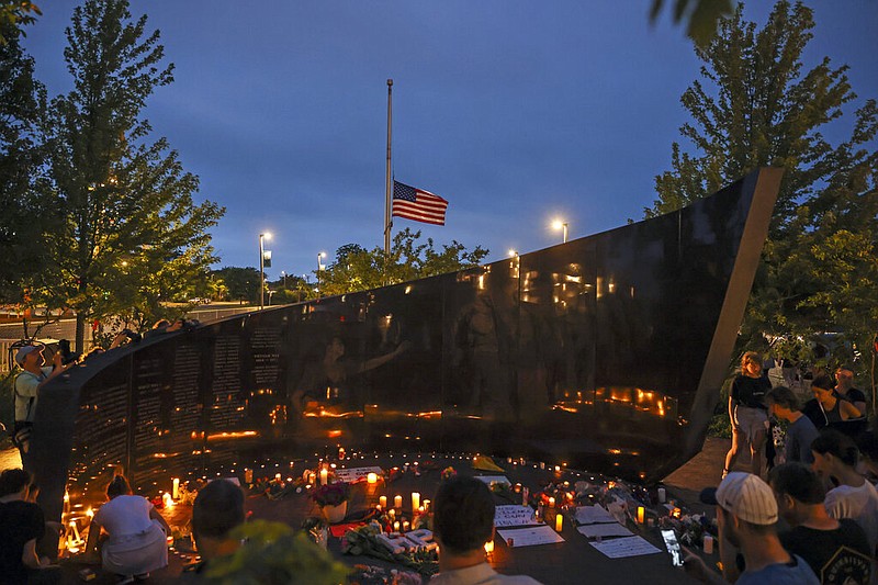 Dozens of mourners gather for a vigil near Central Avenue and St. Johns Avenue in downtown Highland Park, one day after a gunman killed at least seven people and wounded dozens more by firing an AR-15-style rifle from a rooftop onto a crowd attending Highland Park's Fourth of July parade, Tuesday, July 5, 2022 in Highland Park, Ill. (Anthony Vazquez/Chicago Sun-Times via AP)