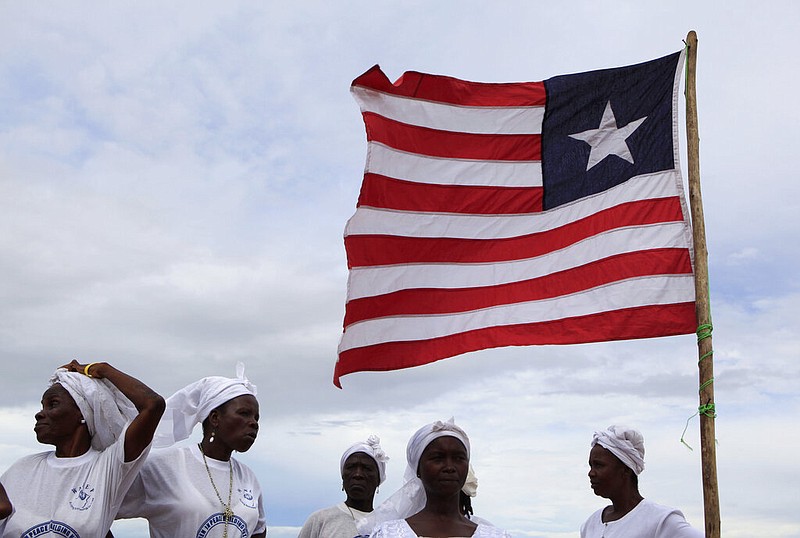 A Liberian flag is visible in Monrovia, Liberia, in this Oct. 10, 2011 file photo. The women are members of the Women In Peacebuilding Network started by Nobel Peace Prize winner Leymah Gbowee. (AP/Rebecca Blackwell)