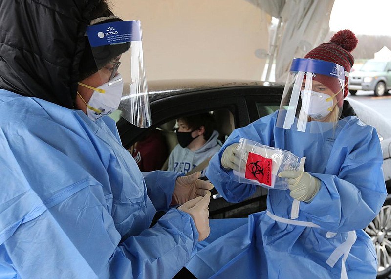 Medical personnel prepare a covid-19 test for Trey Berry, a junior at the University of Arkansas, Fayetteville, in this Jan. 6, 2021 file photo. The testing was part of a drive-up testing clinic hosted by the Arkansas Department of Health in the parking lot across from Baum-Walker Stadium at the corner of Razorback Road and 15th Street in Fayetteville. (NWA Democrat-Gazette/David Gottschalk)