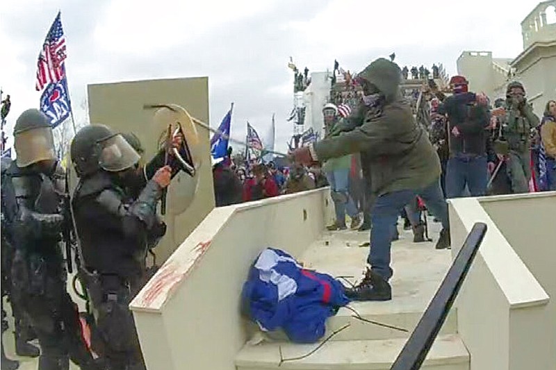 In this image from a Washington Metropolitan Police Department officer's body-worn video camera, and contained in the statement of facts supporting an arrest warrant for Mark Ponder, Ponder strikes an officer with a pole on the West Front of the U.S. Capitol on Jan. 6, 2021, in Washington. Ponder, the man who attacked police officers with poles during the U.S. Capitol riot was sentenced to more than five years in prison on July 26, 2022. (Department of Justice via AP)