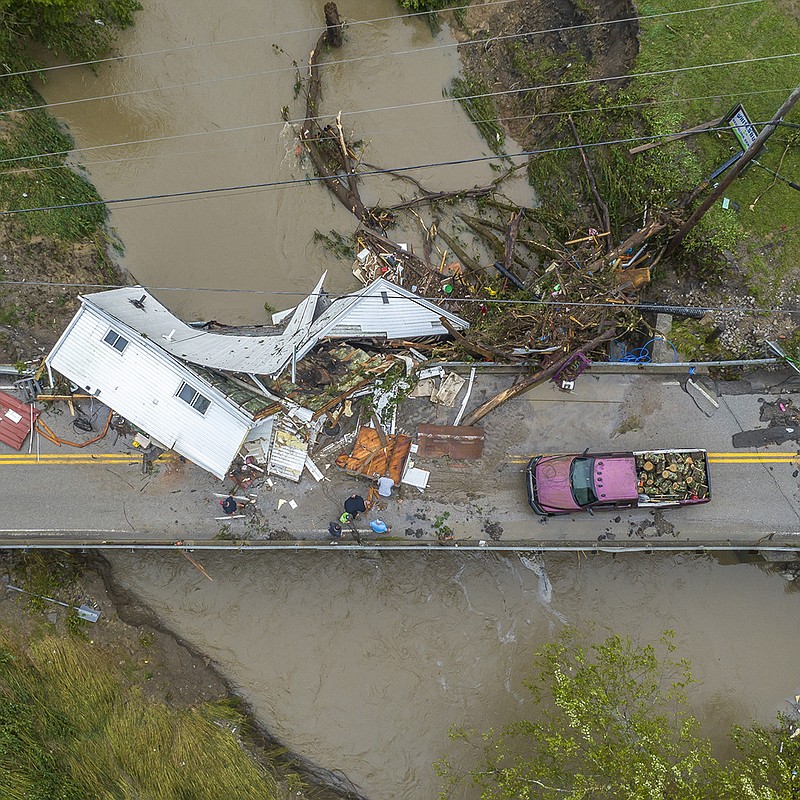 People work to clear a house off a bridge over a debris-strewn creek Friday in Letcher County, Ky. Portions of at least 28 state roads were blocked because of flooding or mudslides, Kentucky Gov. Andy Beshear said. More photos at arkansasonline.com/730lostcreek/.
(AP/Lexington Herald-Leader/Ryan C. Hermens)