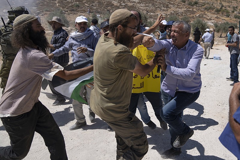 A Palestinian protester punches an Israeli settler Friday during a scuffle between both sides while Palestinian activists blocked the street that bypasses the West Bank village of Mughayer, north of Ramallah.
(AP/Nasser Nasser)